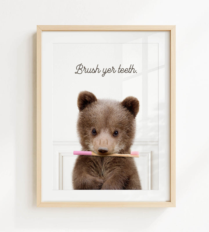 A cute brown bear holding a pink toothbrush in its mouth, with the text "Brush yer teeth" written above it.