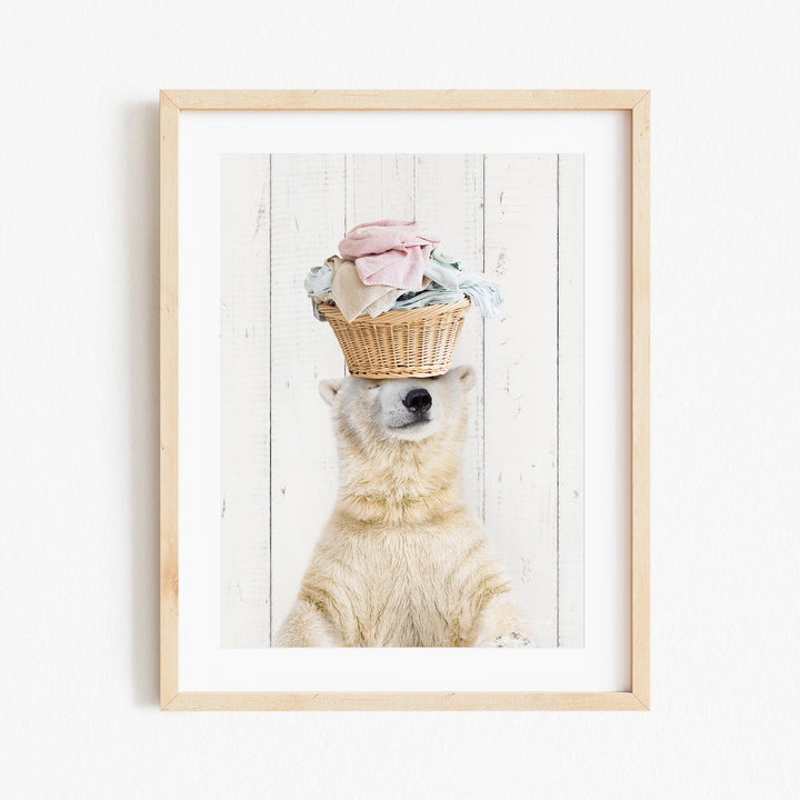 A polar bear balancing a basket of clothes on its head against a white wooden background.