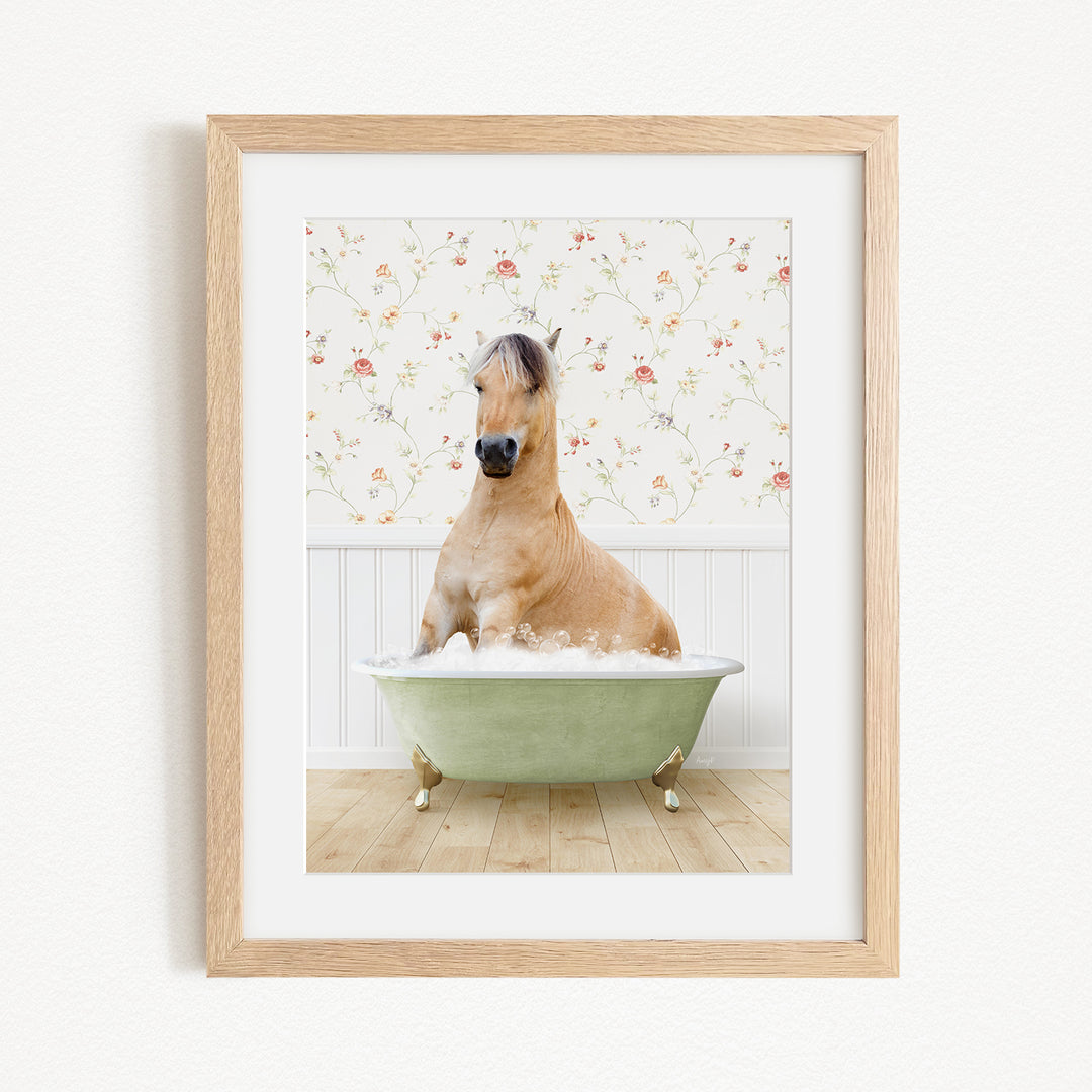 A light brown horse is sitting in a green bathtub filled with water, surrounded by a floral wallpaper.