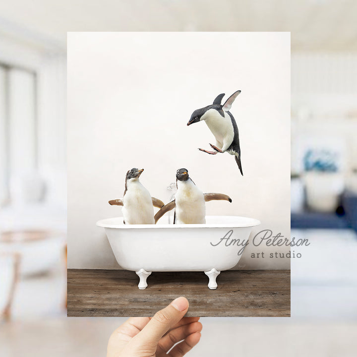 a hand holding a photo of three penguins in a bathtub