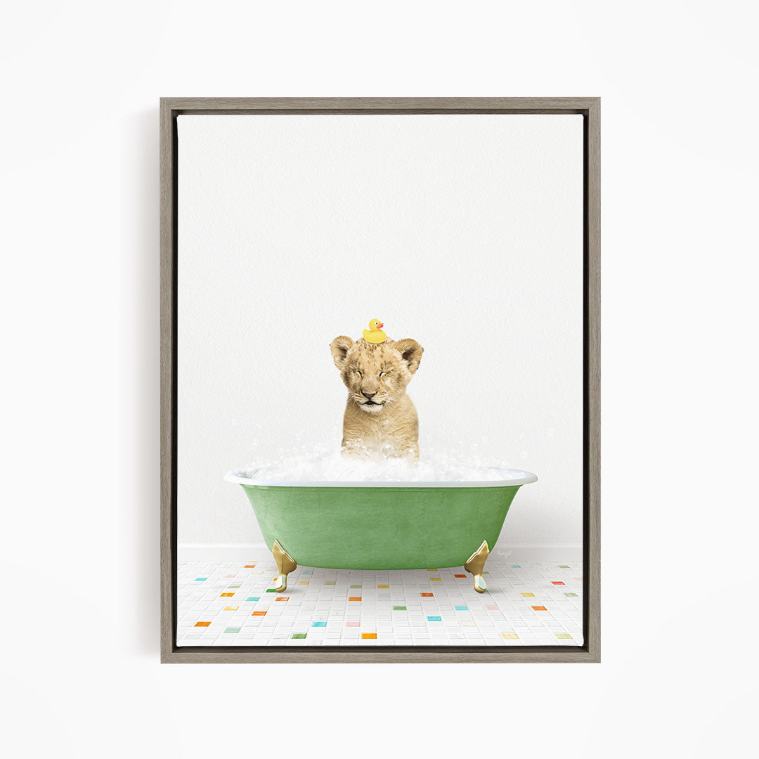 A young lion cub sitting in a green bathtub filled with bubbles, with a yellow rubber duck perched on its head.