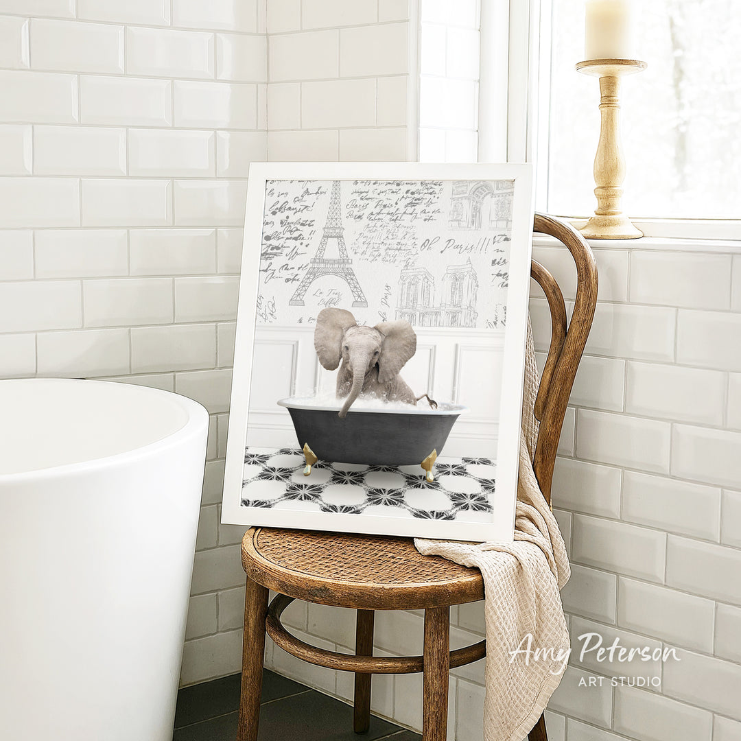 A framed image of an elephant sitting in a bathtub, with a tiled wall and a window in the background.