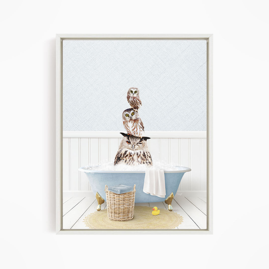 A framed image depicting three owls sitting in a bathtub filled with water, with a yellow rubber duck floating nearby.