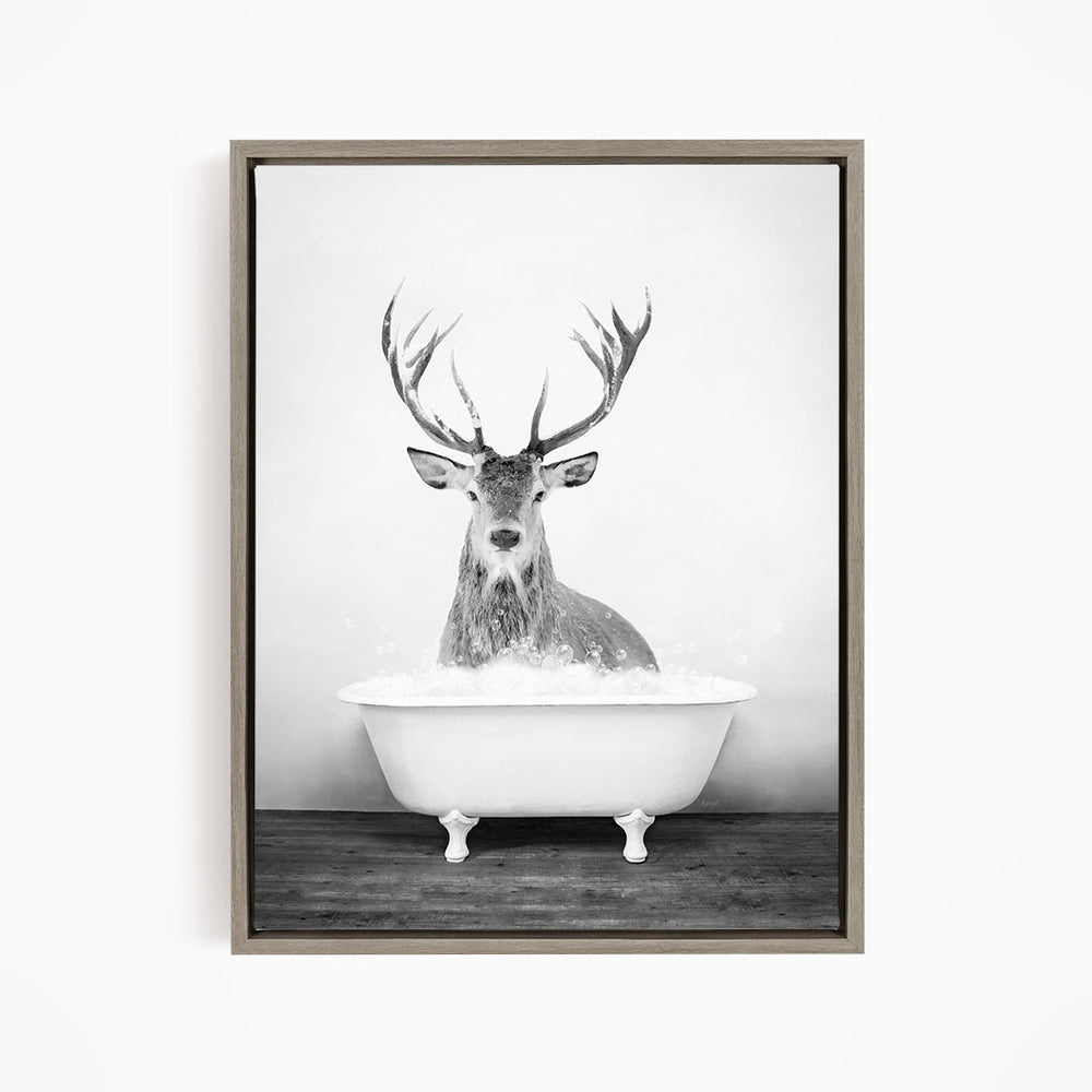 A deer with large antlers is sitting in a bathtub filled with water, creating a whimsical and unexpected scene.