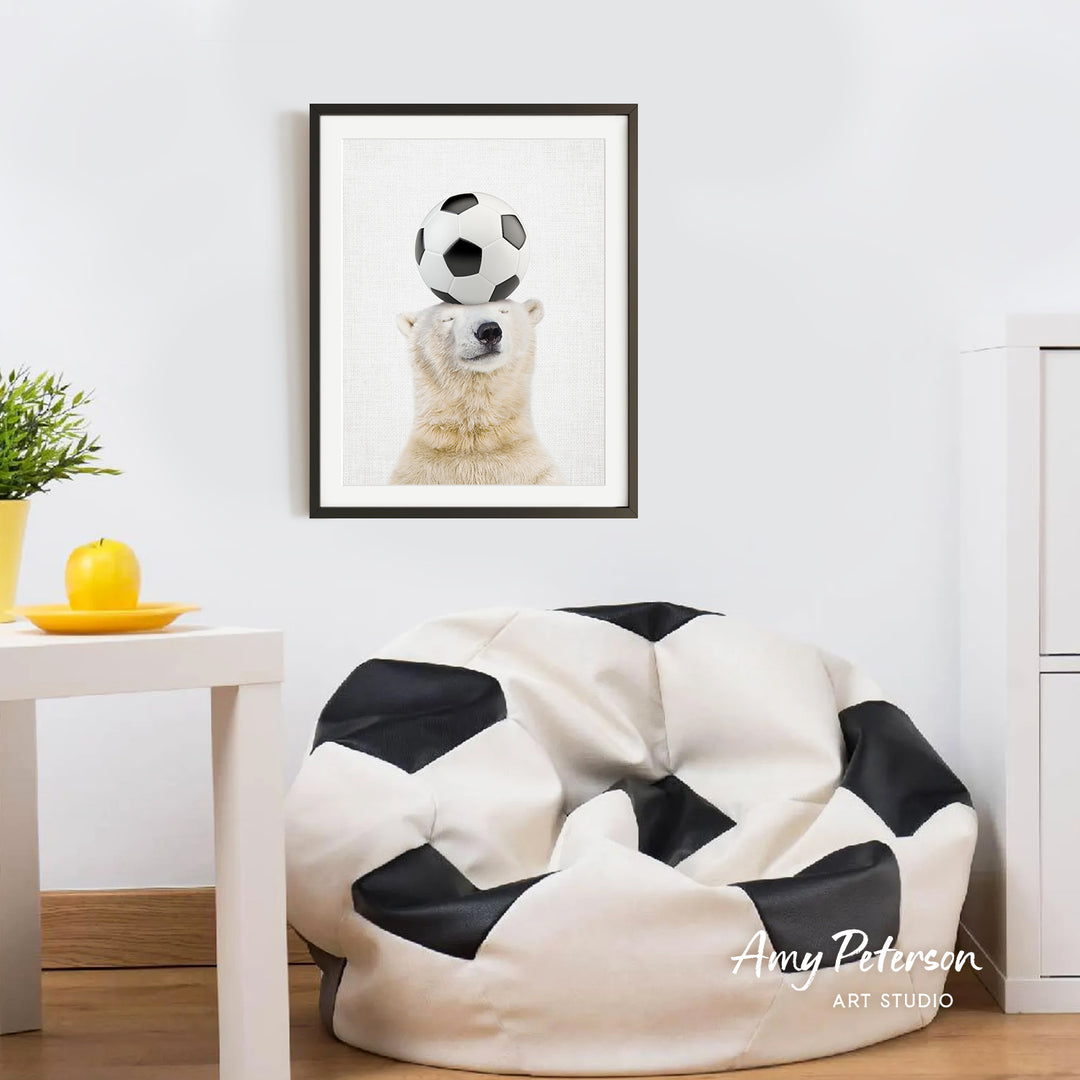 a polar bear balancing a soccer ball on its head, with a framed picture of the polar bear hanging on the wall above a white bean bag chair.