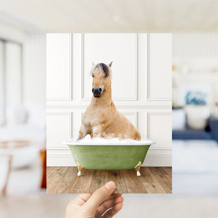 A light brown horse sitting in a green bathtub filled with water, with a blurred background suggesting a living room setting.