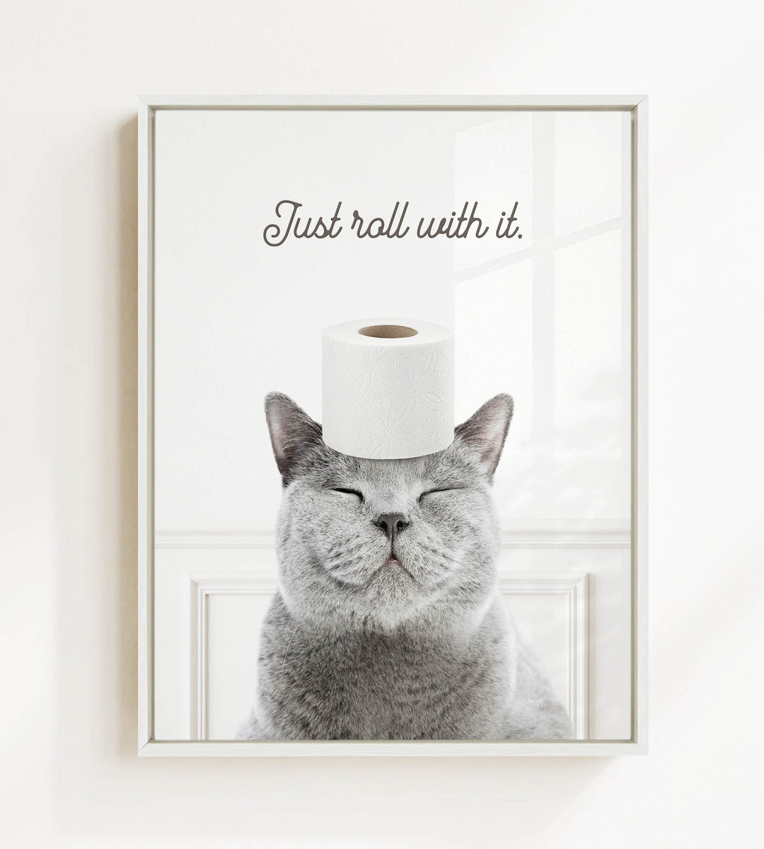 A gray cat with its eyes closed and a roll of toilet paper on its head, with the text "Just roll with it."