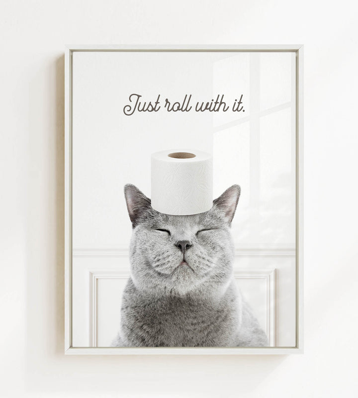 A gray cat with its eyes closed and a roll of toilet paper on its head, with the text "Just roll with it."