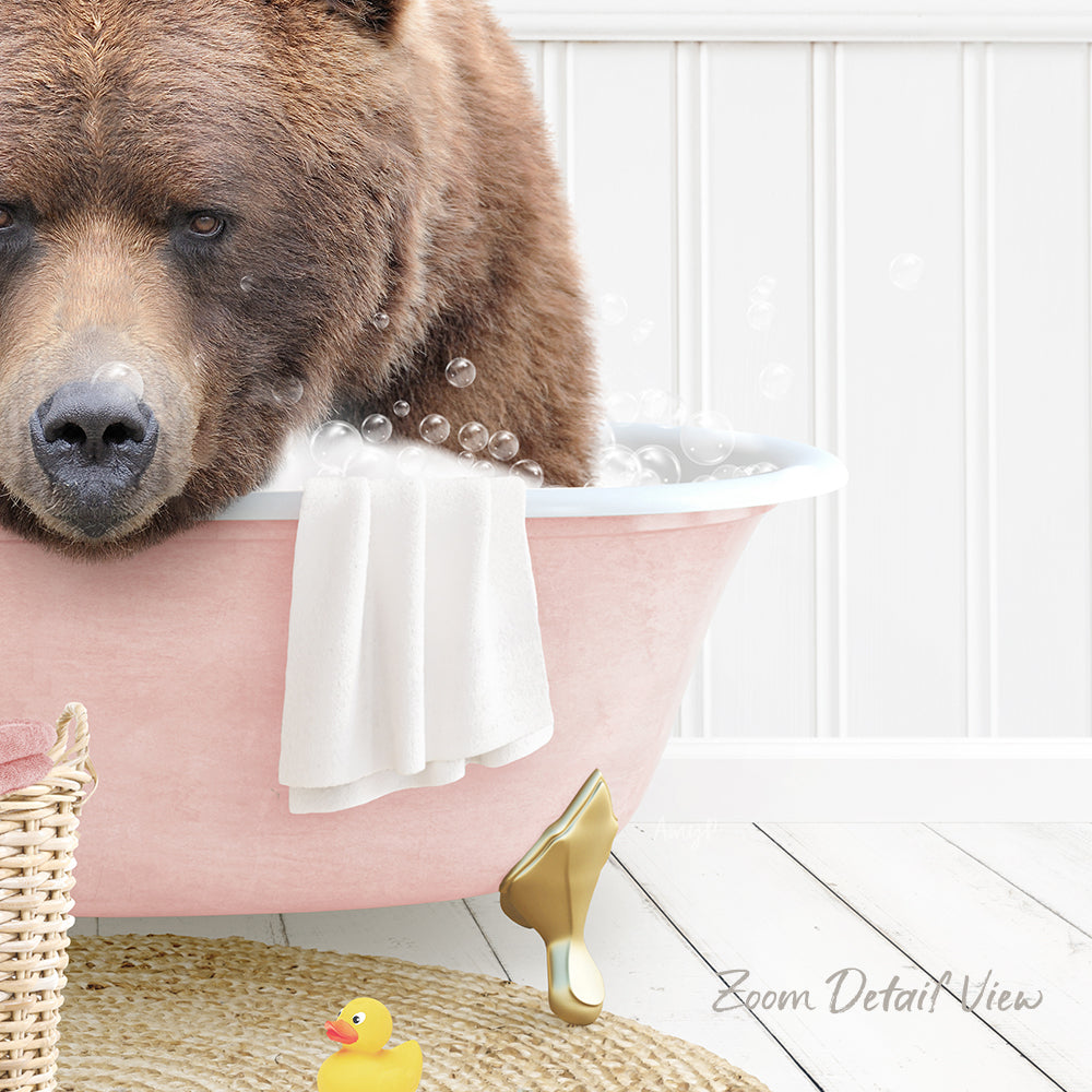 A brown bear is sitting in a pink bathtub filled with bubbles, surrounded by a yellow rubber duck and a white towel.