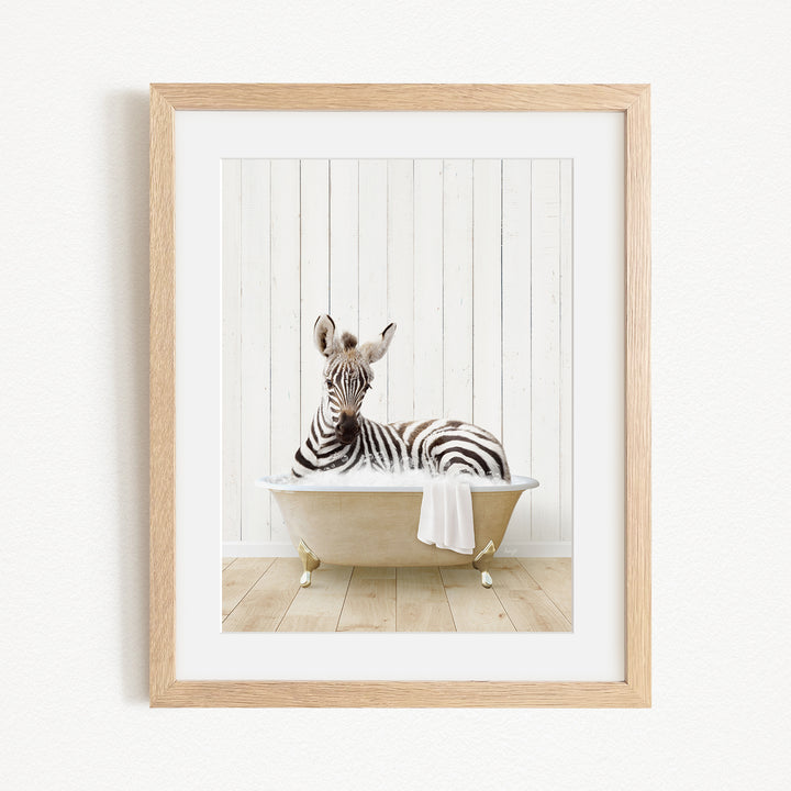 A zebra is sitting in a bathtub filled with water, surrounded by a wooden frame.