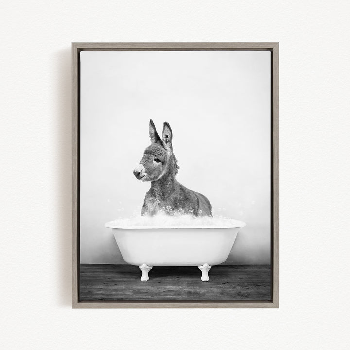 A donkey sitting in a white bathtub filled with bubbles, looking directly at the camera.