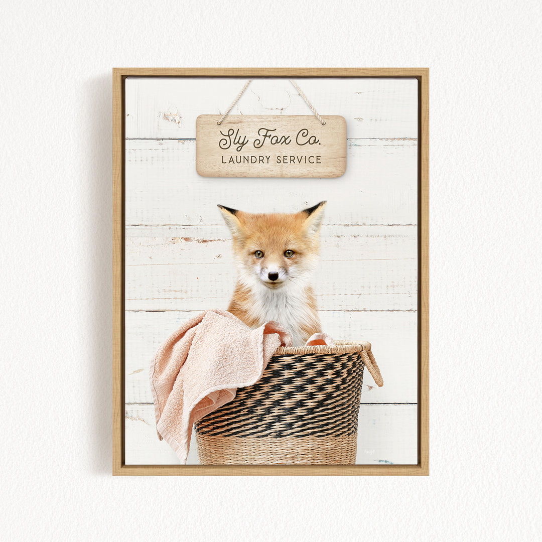 A framed image of a red fox sitting in a woven laundry basket, with a sign above it that reads "Laundry Service".