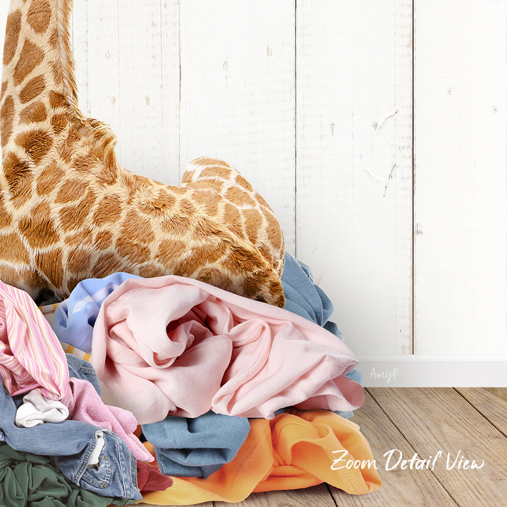 A pile of colorful clothes, including a giraffe stuffed animal, is displayed against a white wooden background.