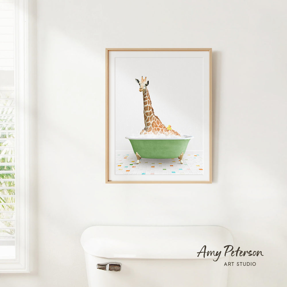 A framed watercolor painting of a giraffe sitting in a green bathtub, with a white toilet and a window in the background.
