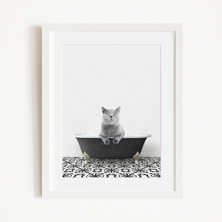 A gray cat sitting in a black bathtub, with a patterned tile floor in the foreground.