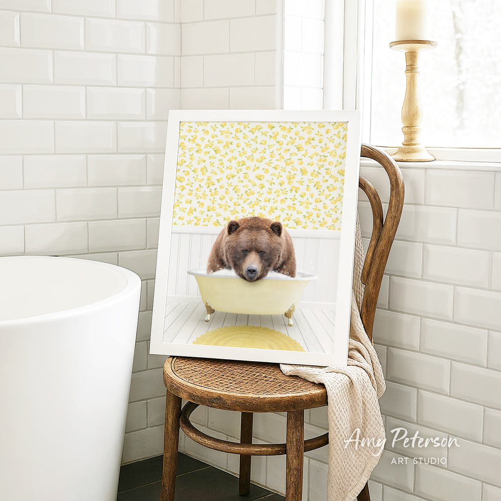 A framed image of a bear sitting in a bathtub, with a yellow floral pattern on the wall behind it.