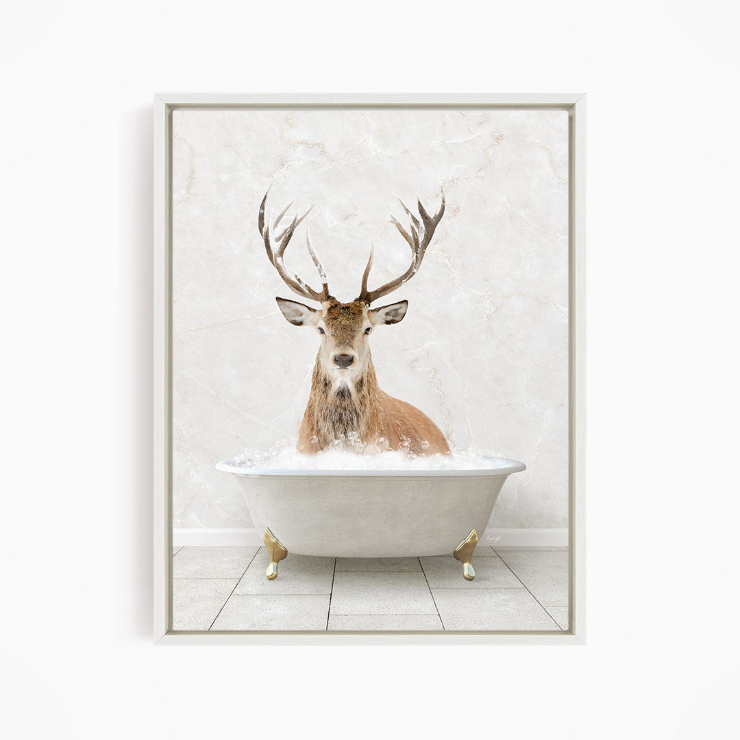 A deer with large antlers is sitting in a white bathtub filled with water, creating a whimsical and unexpected scene.