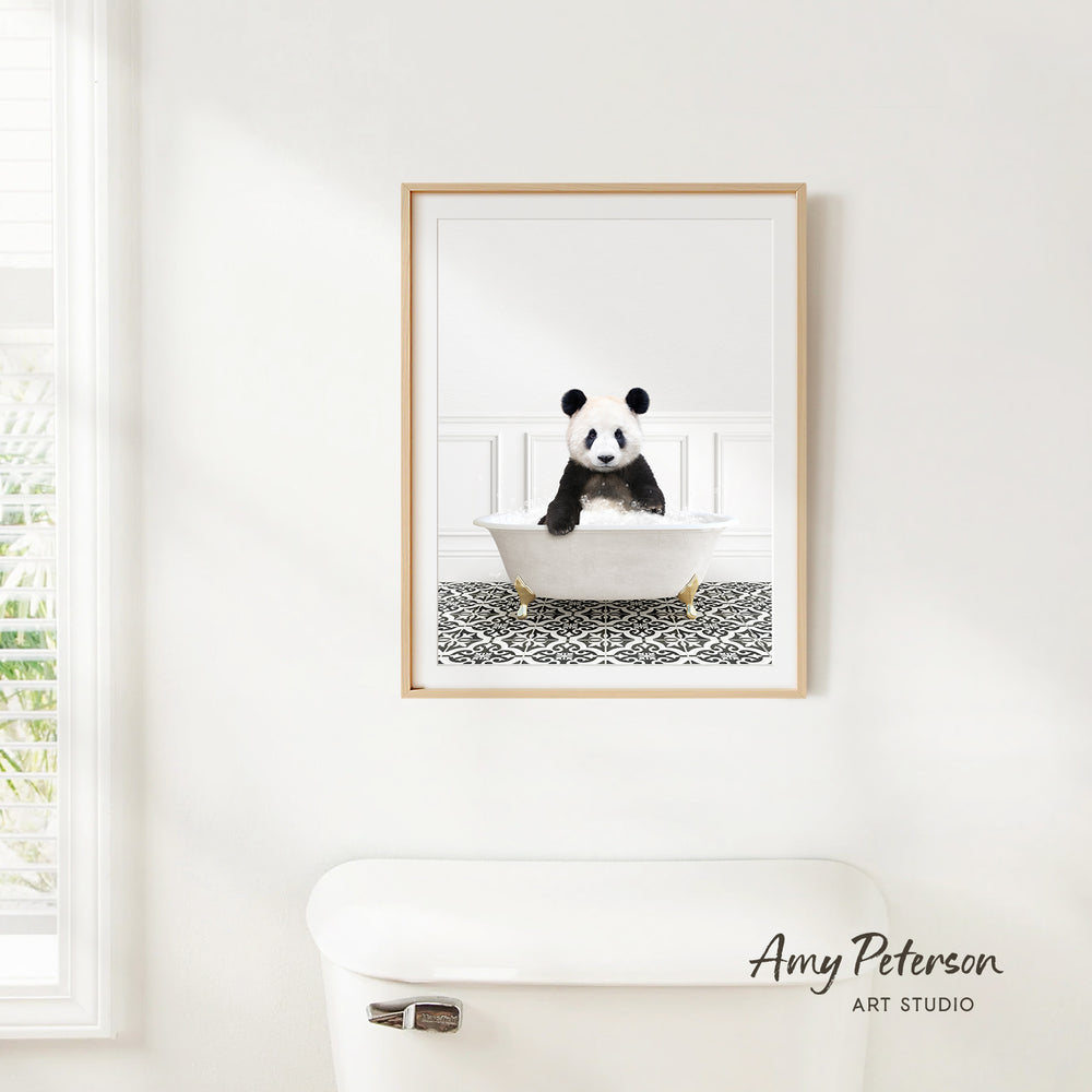 A framed image of a panda bear sitting in a bathtub is hanging on a white wall.