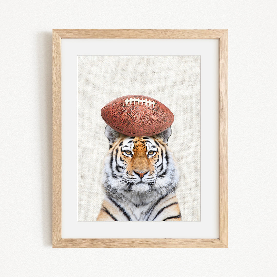 A tiger wearing a football helmet and standing in front of a plain background.