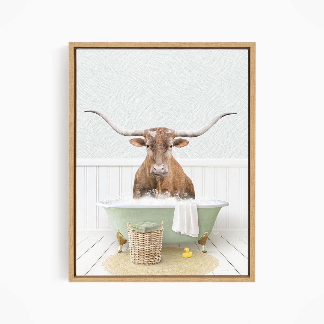 A brown bull with long horns is sitting in a green bathtub filled with bubbles, surrounded by a basket of rubber ducks and a towel.