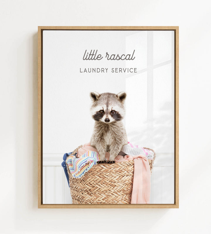 A raccoon sitting in a woven laundry basket, with the text "little raccal Laundry Service" displayed above the image.