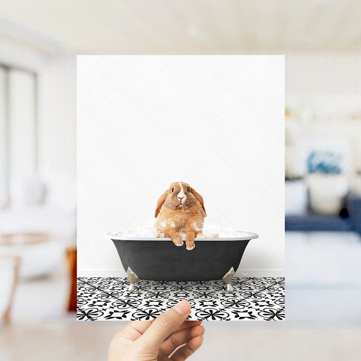A brown rabbit sitting in a bathtub filled with water, surrounded by a black and white patterned floor.