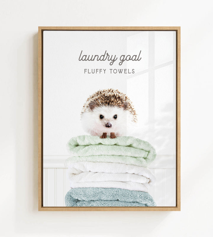 A framed image of a hedgehog sitting atop a stack of fluffy towels, with the text "laundry goal" and "FLUFFY TOWELS" written above it.