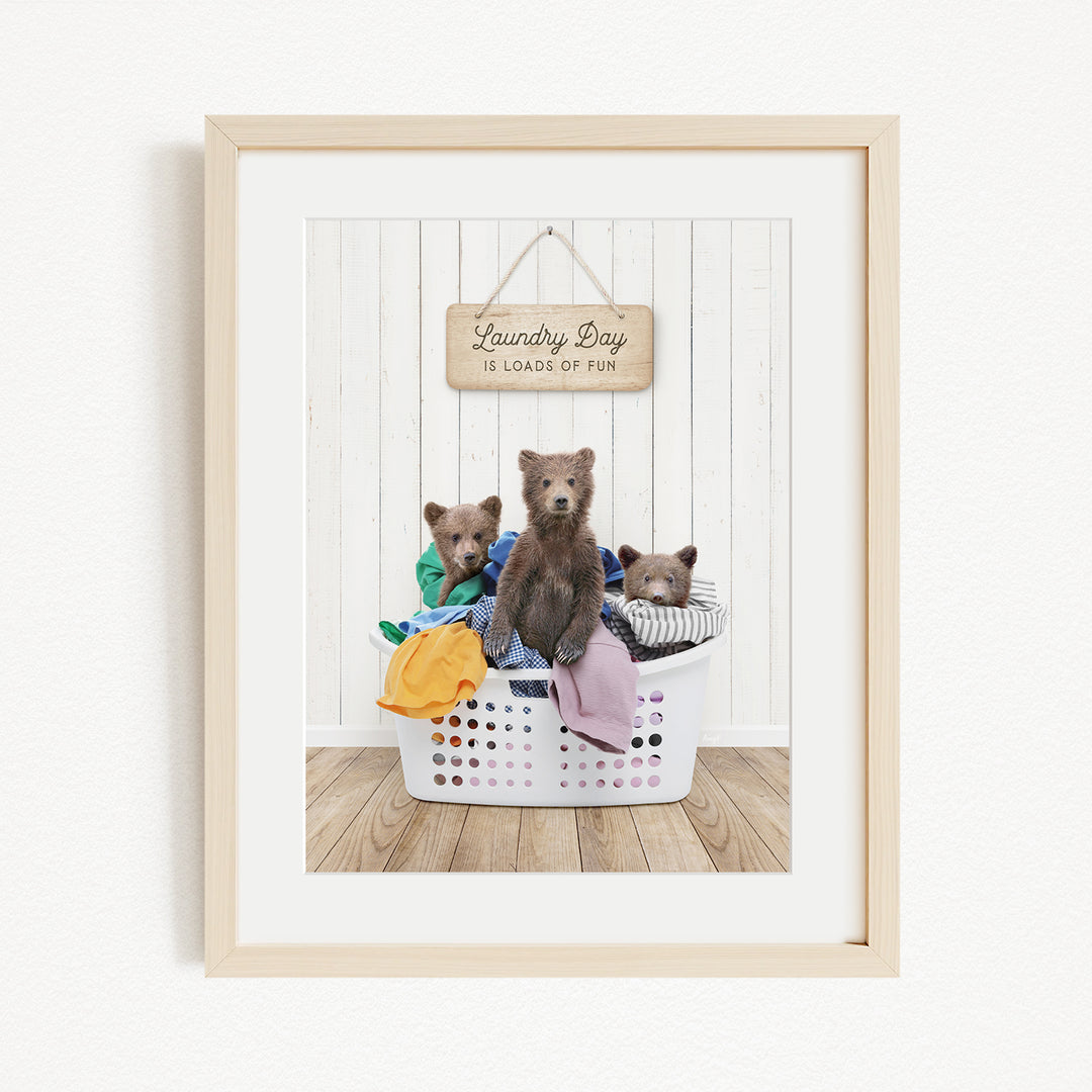 A framed image depicting three bears sitting in a laundry basket, with a sign above them that reads "Laundry Day is loads of fun".