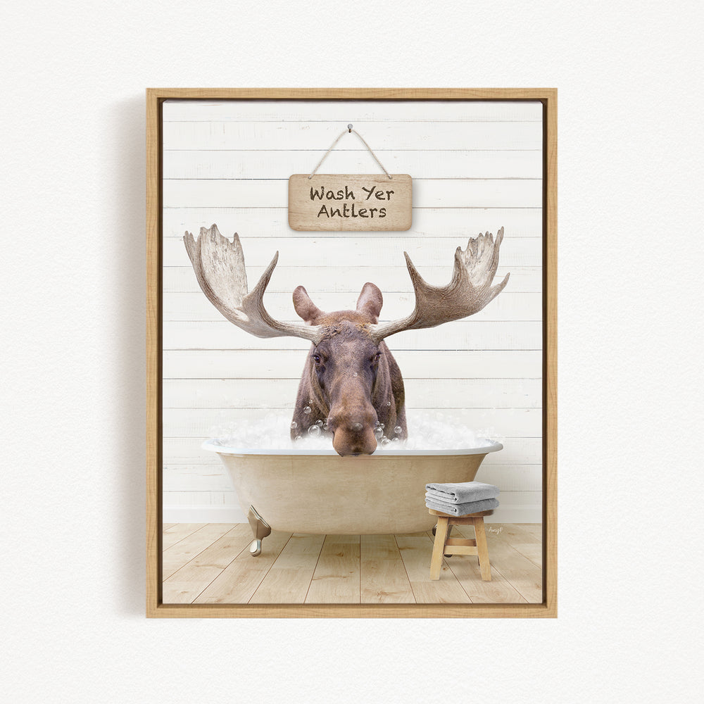 A moose is sitting in a bathtub filled with water, with a sign above it that says "Wash Yer Antlers".