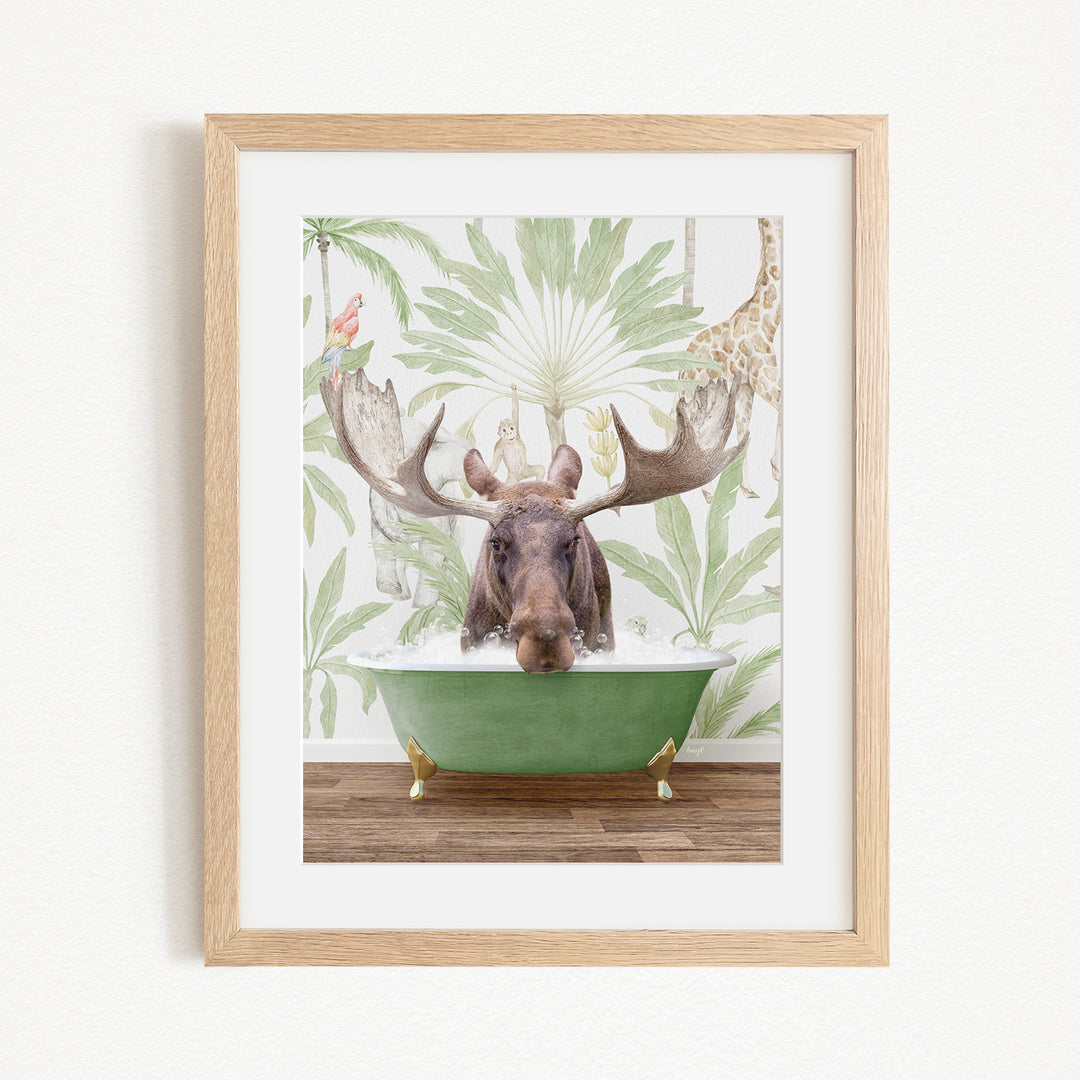 A moose with large antlers is sitting in a green bathtub, surrounded by a tropical wallpaper with palm leaves and a giraffe.