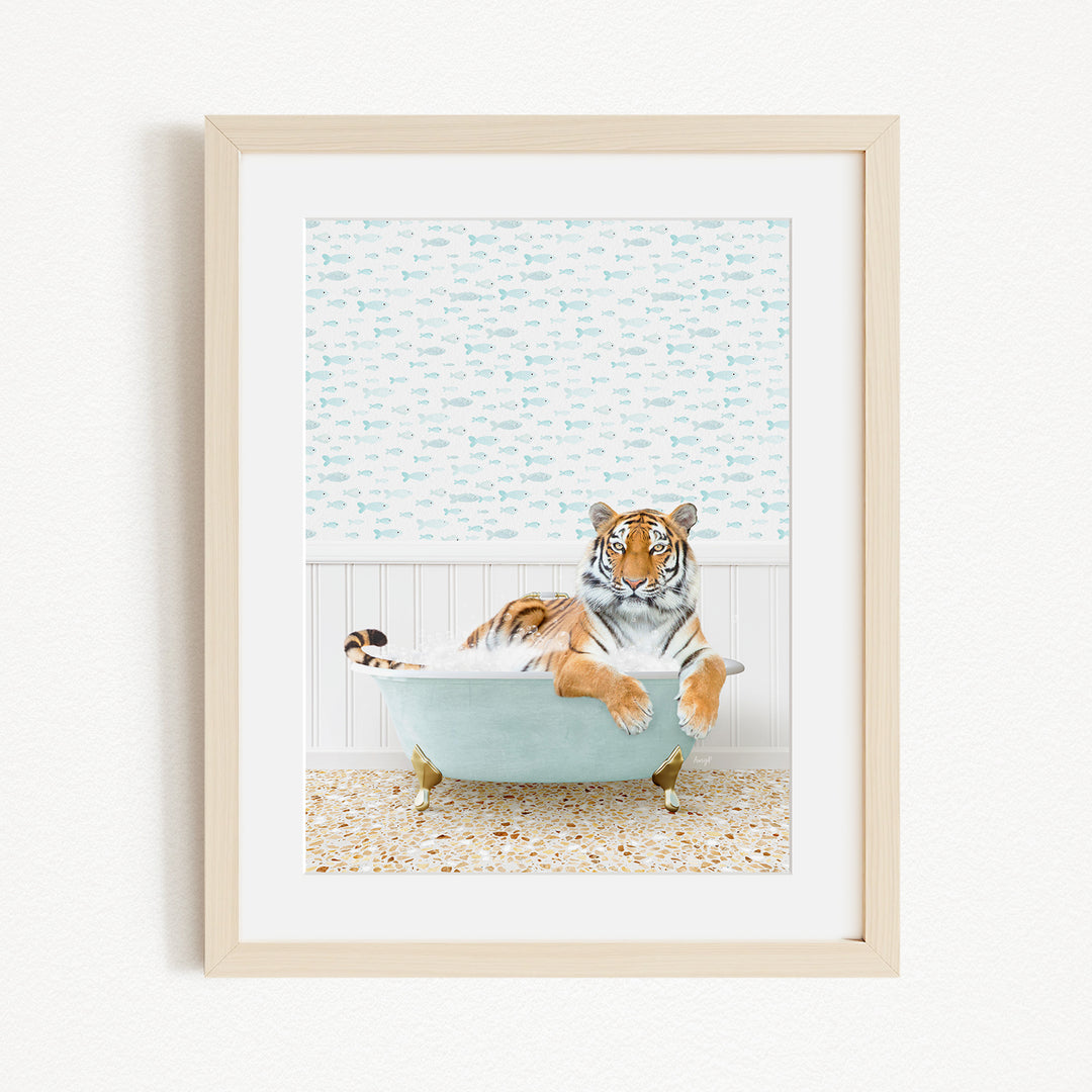 A tiger is sitting in a light blue bathtub, surrounded by a patterned wall and a tiled floor.