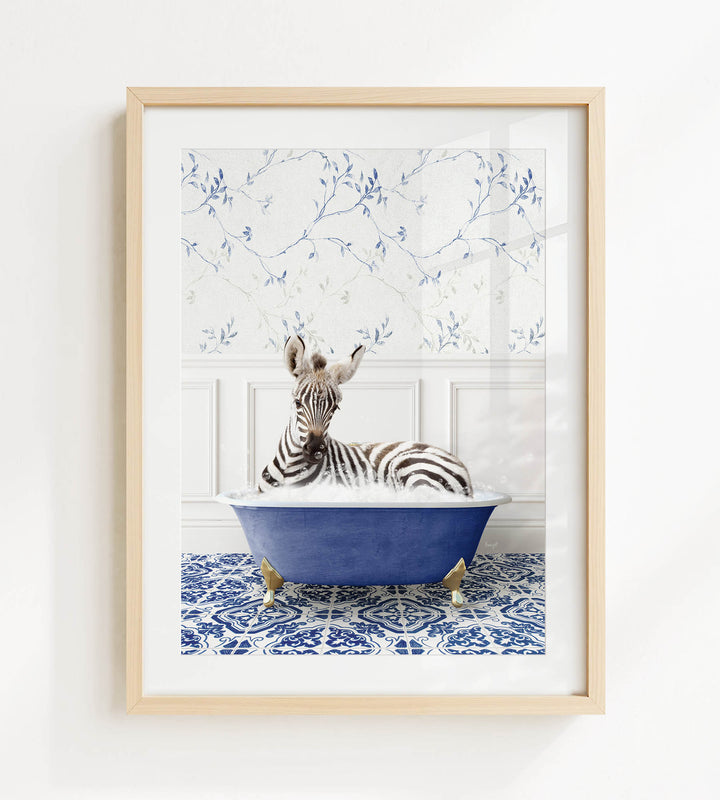 A zebra is sitting in a blue bathtub, surrounded by a patterned tile floor and a white wall with blue floral wallpaper.