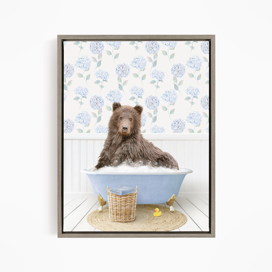 A brown bear sitting in a blue bathtub filled with bubbles, surrounded by a wicker basket and yellow rubber ducks.