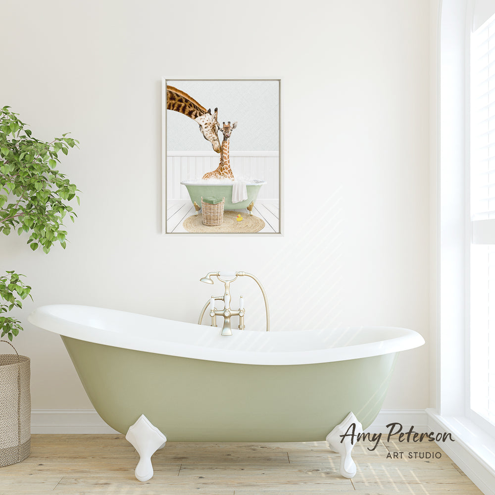 A framed image of a giraffe sitting in a bathtub is displayed on the wall above a green clawfoot bathtub in a bathroom.