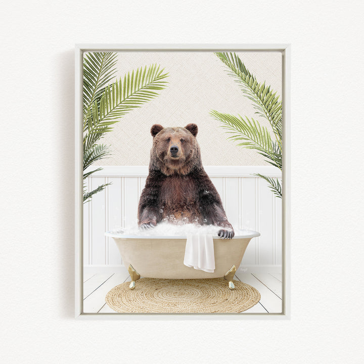 A brown bear sitting in a white bathtub filled with bubbles, surrounded by green palm leaves.
