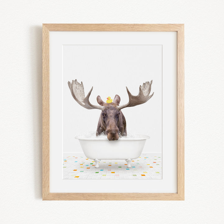 A moose with large antlers is sitting in a bathtub, with a yellow rubber duck perched on its head.