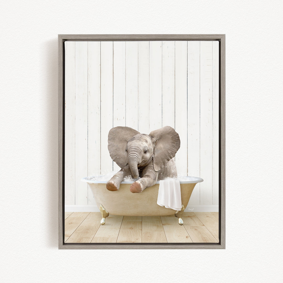 A baby elephant sitting in a bathtub, with its trunk in the water, against a white wooden wall.