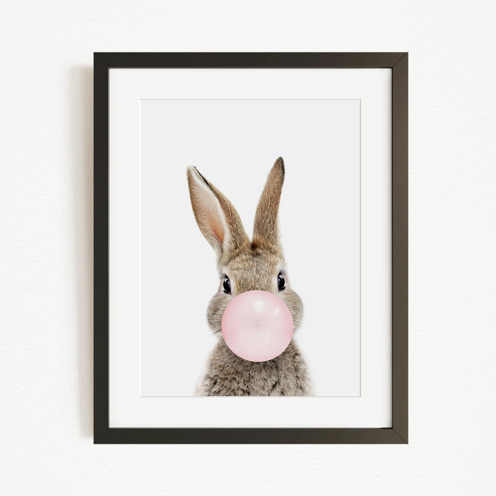 A cute rabbit blowing a pink bubble with its nose.