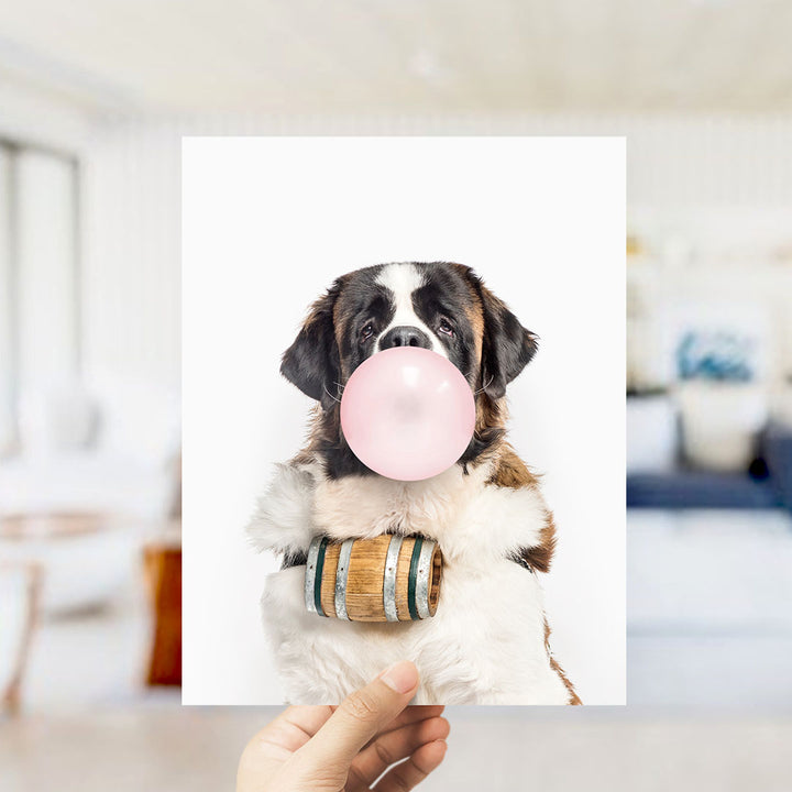 A dog wearing a wooden barrel around its neck is blowing a bubble with a pink bubble gum bubble.