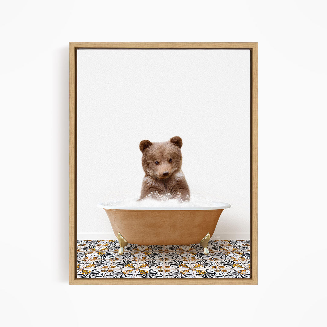 A cute brown bear cub sitting in a bathtub filled with bubbles, surrounded by a patterned tile floor.
