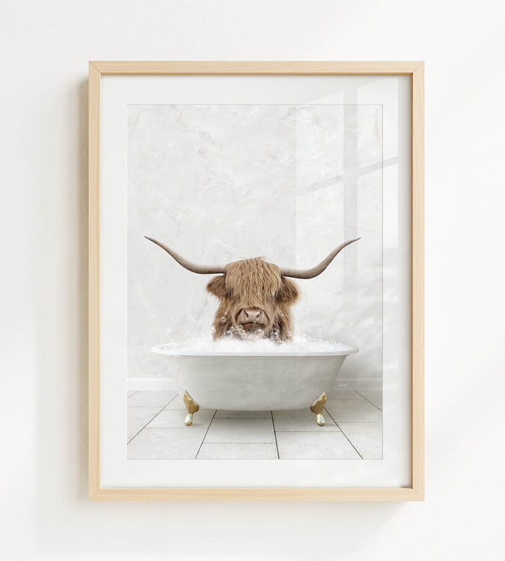 A framed image depicting a Highland cow with long horns sitting in a white bathtub filled with water.