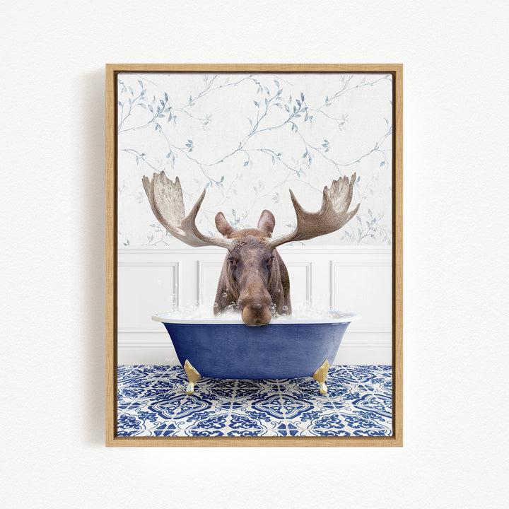 A moose with large antlers is sitting in a blue bathtub filled with water, surrounded by a blue and white patterned tile floor.