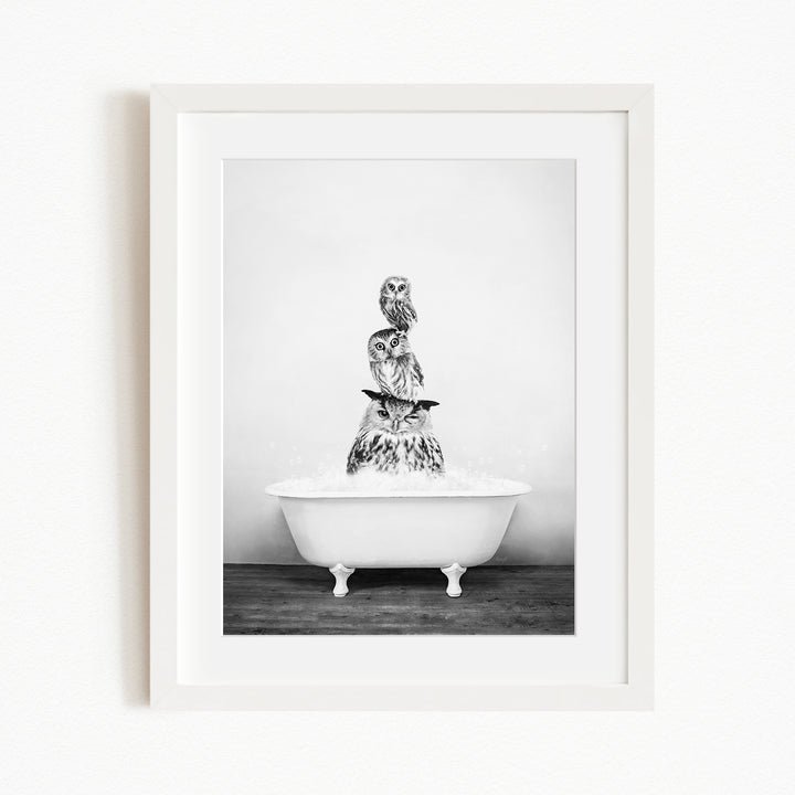 A black and white image of a bathtub filled with water, with a stack of three owls perched on top of it.