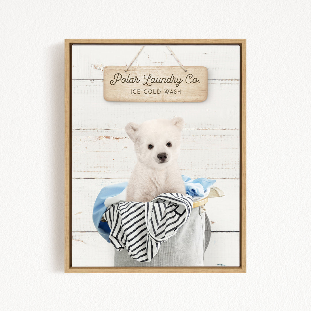 A white polar bear sitting in a bucket filled with clothes, with a wooden sign above that reads "Polar Laundry Co. ICE COLD WASH".