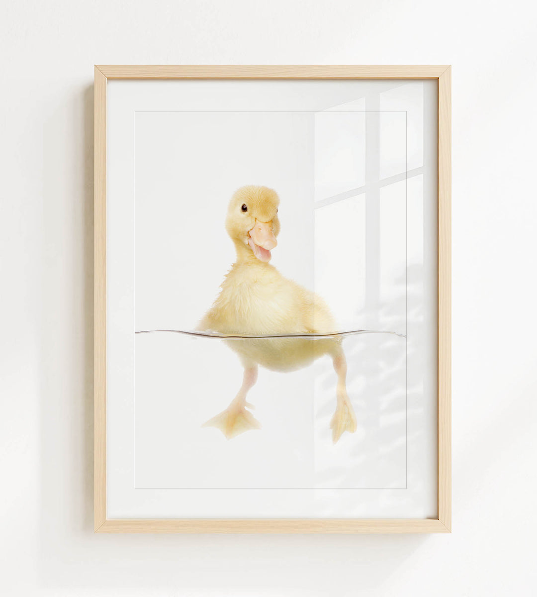 A cute yellow duckling swimming in a clear container, with its head and feet visible above the water's surface.