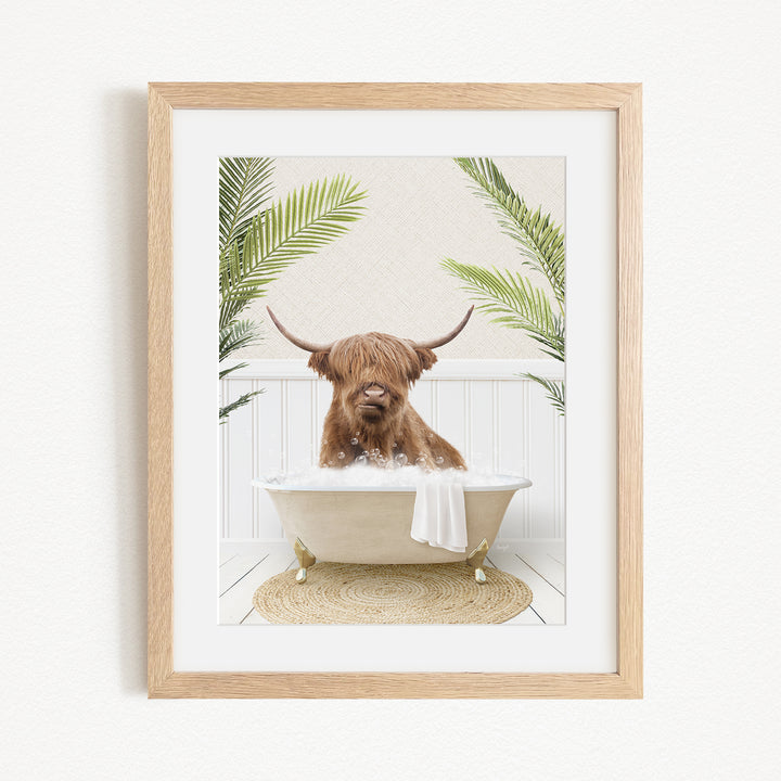A brown cow with long horns is sitting in a white bathtub filled with water, surrounded by green plants.