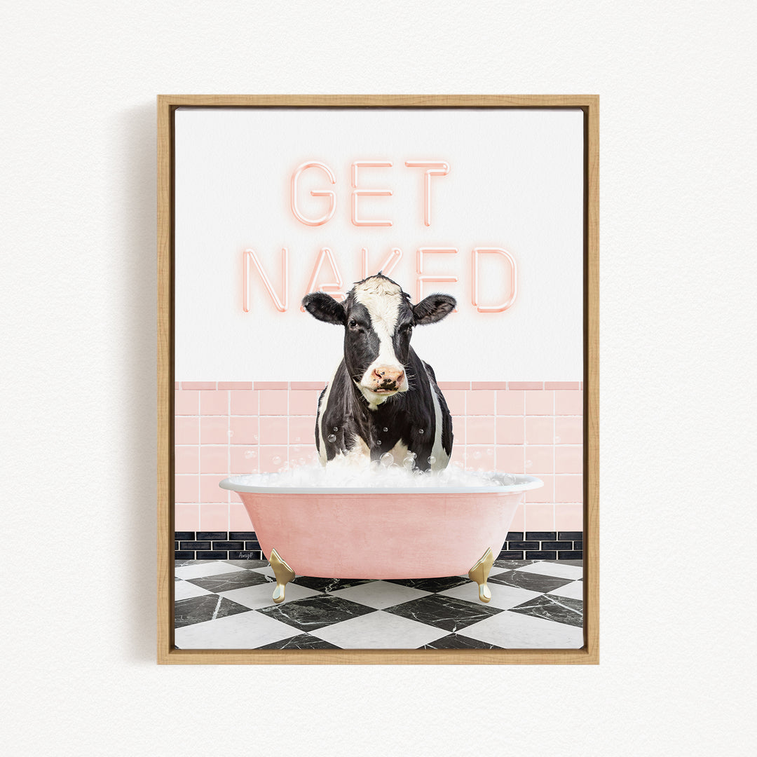 A black and white cow is sitting in a pink bathtub filled with water, with the words "GET NAKED" written in neon pink letters above the cow.