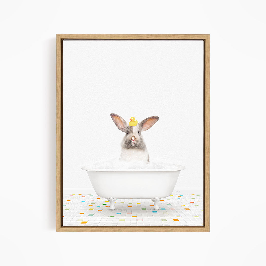 A white rabbit sitting in a white bathtub filled with bubbles, with a yellow rubber duck perched on its head.