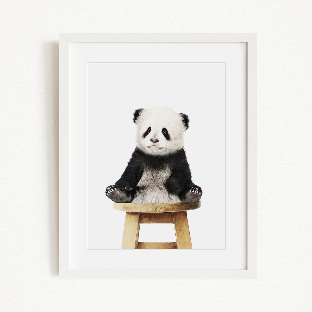 A cute panda sitting on a wooden stool.