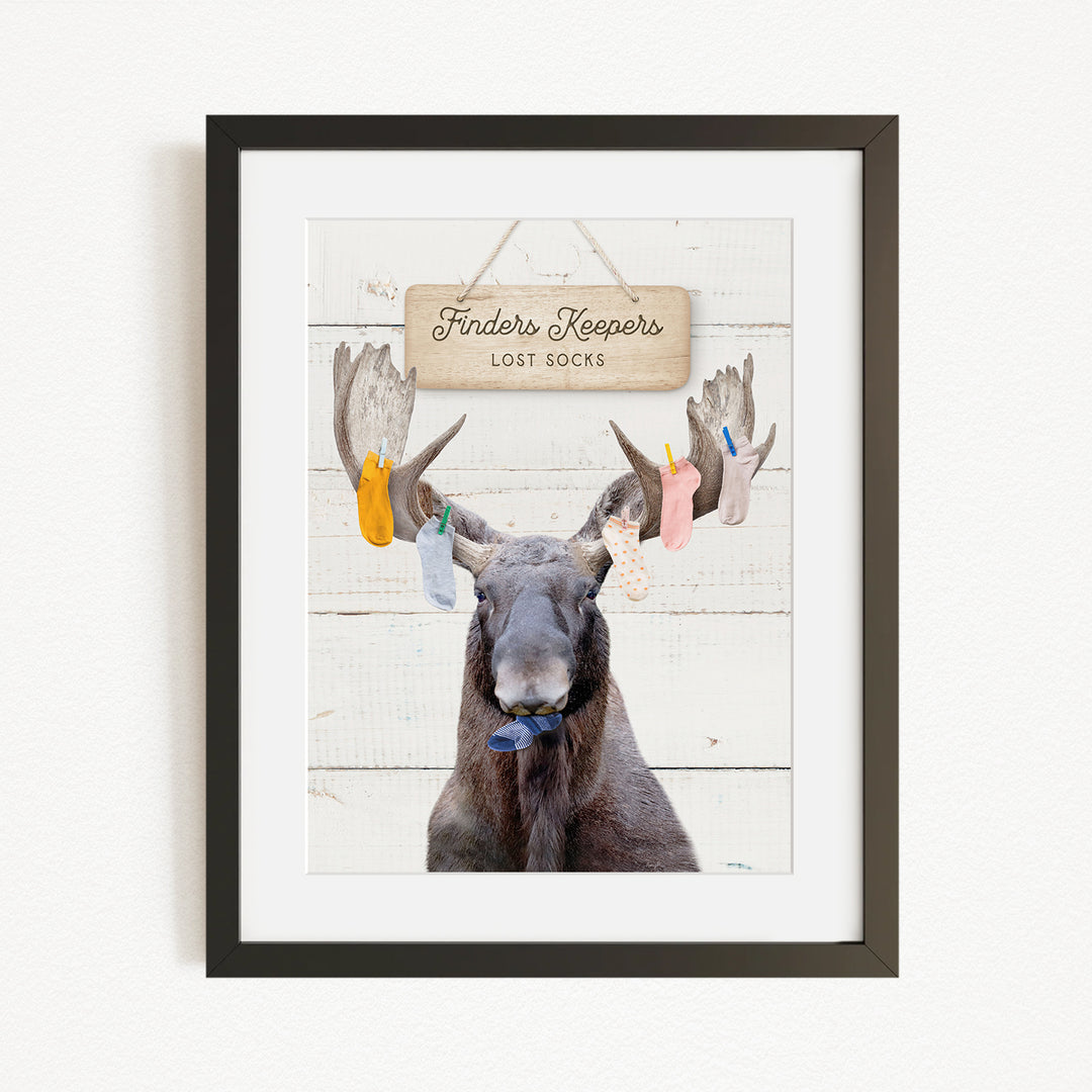 A framed image of a moose with a sign that says "Finders Keepers Lost Socks" hanging above it.
